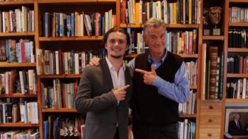 Sir Michael Palin posing with a man and both are smiling at pointing at each other