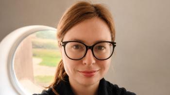 A woman wearing glasses, smiling