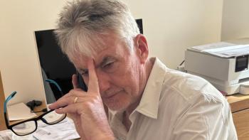 A man looking defeated, with a phone to his ear and his other hand holding a pair of glasses and touching his forehead