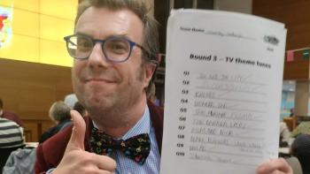 A man holding a piece of paper in one hand and doing a thumbs up with the other