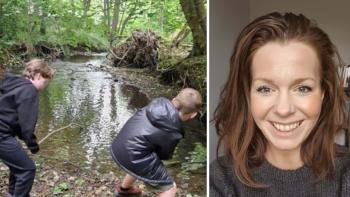 Two boys next to a woodland stream. A smiling woman's face is net to them