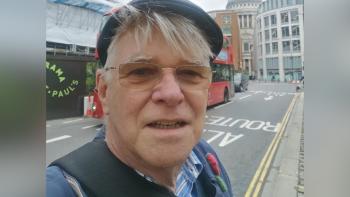 A man with a London street as a backdrop, smiling