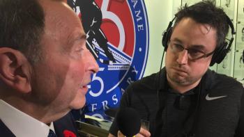 A man wearing headphones and holding a microphone in front of another man