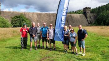 A group of people in an outdoor setting standing beside a banner