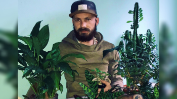 A man surrounded by numerous pot plants