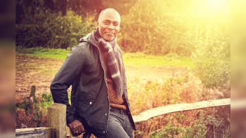A man leaning against a fence in an outdoor setting