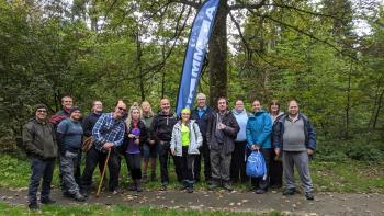 A group of people in an outdoor setting standing beside a banner