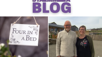 A sign saying 'Four In A Bed'and a man and a woman standing, looking at the camera and smiling
