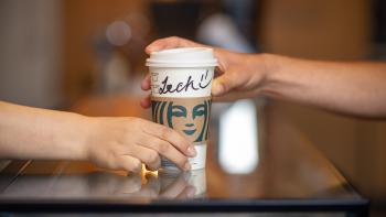 A Starbucks coffee cup handed over the counter