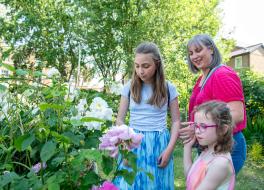 A mother and her two young daughters looking at flowers