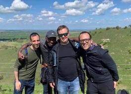 Four men in an outdoor setting linking arms