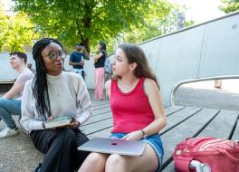 what to do when speech therapy isn't working Two women seated in an outside setting and chatting, with other people in the background