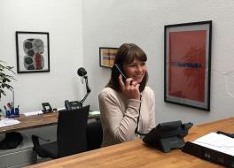 A woman at a desk speaking into a phone