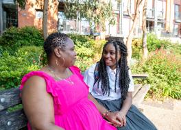 A mother sitting with her daughter on a park bench and chatting