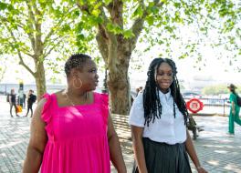 A mother walking with her daughter outside and chatting