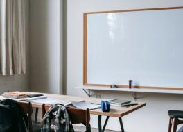 An empty classroom focusing on a whiteboard and a teacher's desk