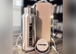 A metal water bottle on a desk surrounding by fairy lights