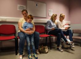 Mothers with children on their laps sitting in a doctor's waiting room