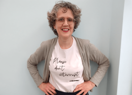A woman with her hands on her hips, smiling for the camera. She is wearing a t-shirt that reads 'Please don't interrupt'.
