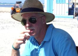 A man on a beach wearing a straw hat and sunglasses
