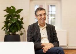 A man sitting on a chair, smiling and looking at something to his left