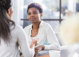 A woman in a therapy setting, talking to another woman, whose face we cannot see
