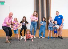 A group of children smiling, with two grown ups 