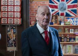 A man in a suit standing in a museum looking at the camera