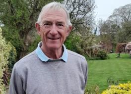 A man standing in a garden and smiling
