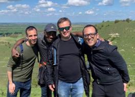 Four men standing together and smiling in the coountryside