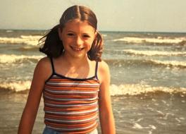 A girl on beach with waves behind her