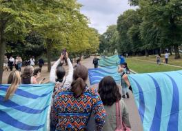 A group of people marching through a park holding flags