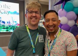 Two men wearing lanyards standing together and smiling