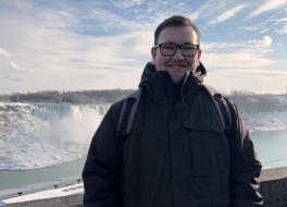 A man standing in front of a waterfall and smiling