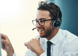 A man in a call centre wearing a phone headset and smiling