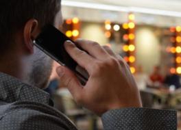 The back of a man's head as he speaks into a mobile phone. 