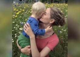 A mother holding her young son in a meadow surrounded by flowers