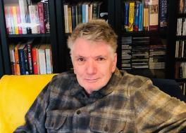 A man sitting in front of a bookshelf and smiling
