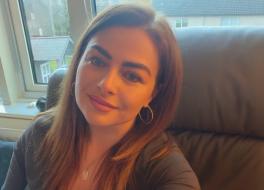 A woman sitting on a chair in front of a window behind her