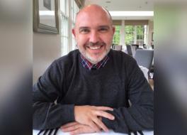 A man sitting at a restaurant table and smiling