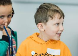 A young boy looking to the right, with another boy behind, looking to the left