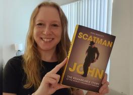 A woman holding a book and smiling