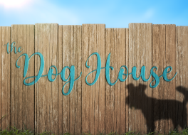 A wooden fence with the shadow of a dog on it, and handwriting that reads 'The Dog House'