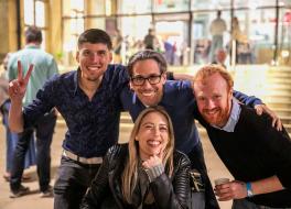 Three men and a woman huddled together and smiling
