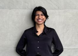 A woman leaning against a wall and smiling