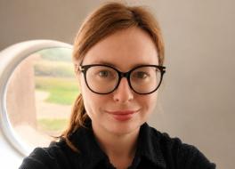 A woman wearing glasses, smiling