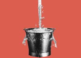 A bucket, with water pouring into it and spilling over the sides