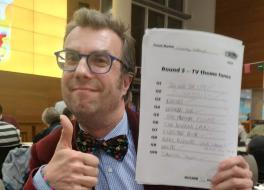 A man holding a piece of paper in one hand and doing a thumbs up with the other