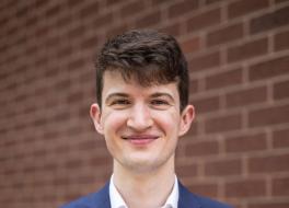 A man in front of a brick wall, smiling