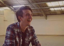 A man with a book open, laughing